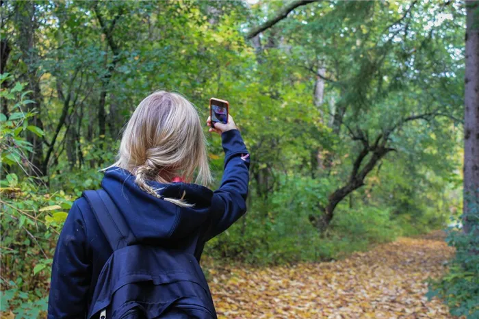 Девушка фотографирует себя на телефон подняв руку вверх